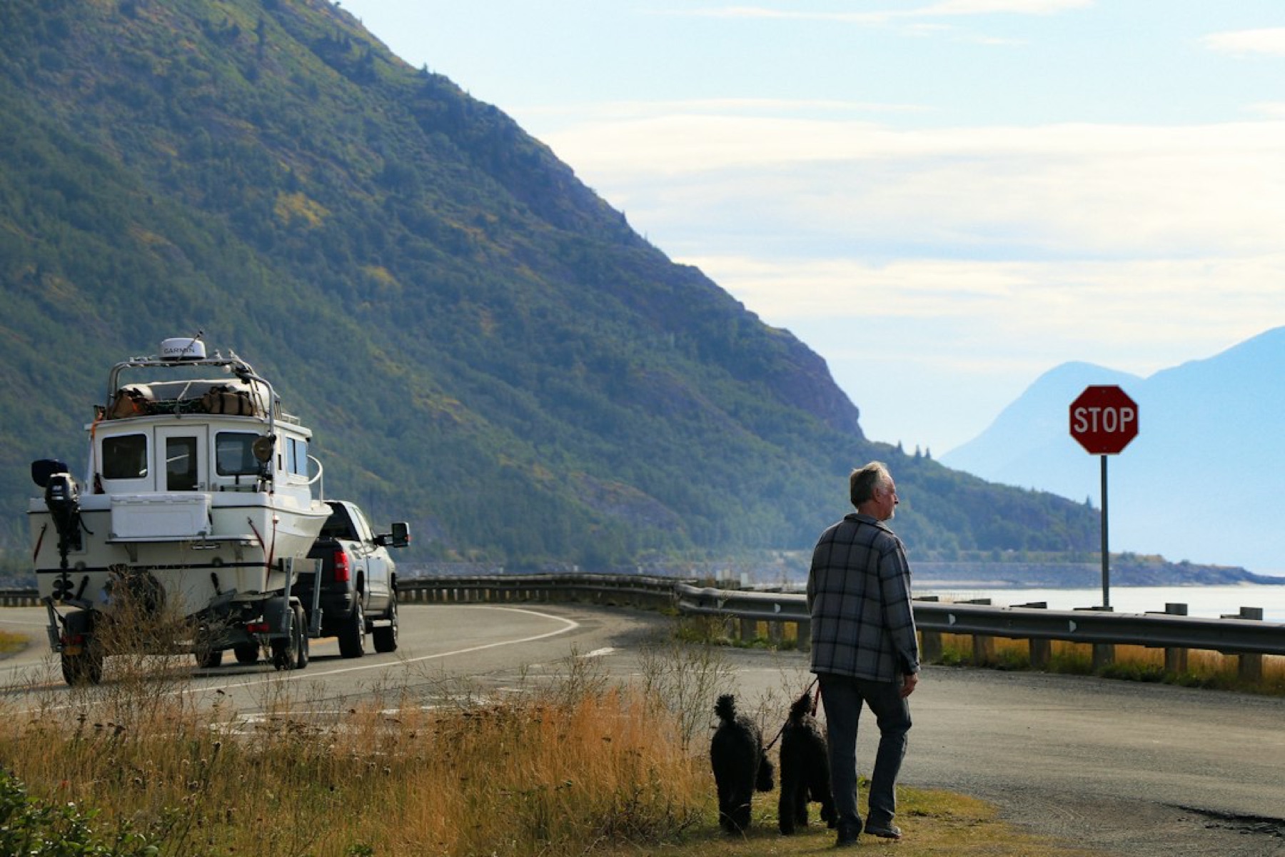 Pick-up qui tracte un bateau sur remorque, arrêté à un panneau stop en bord de route