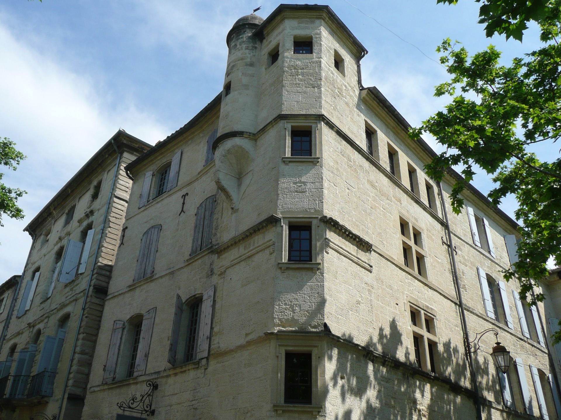 immeuble ancien à tourelle d'angle sur la place aux Herbes, à Uzès, façade en pierre avec volets