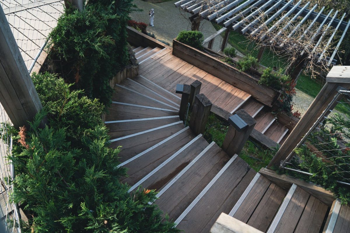 Terrasse et escalier en bois vus du dessus entoures de vegetation