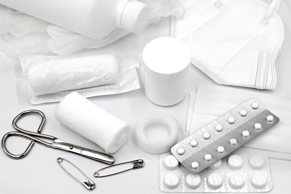 Trousse de secours a plat avec bandages, ciseaux et comprimes sur fond blanc