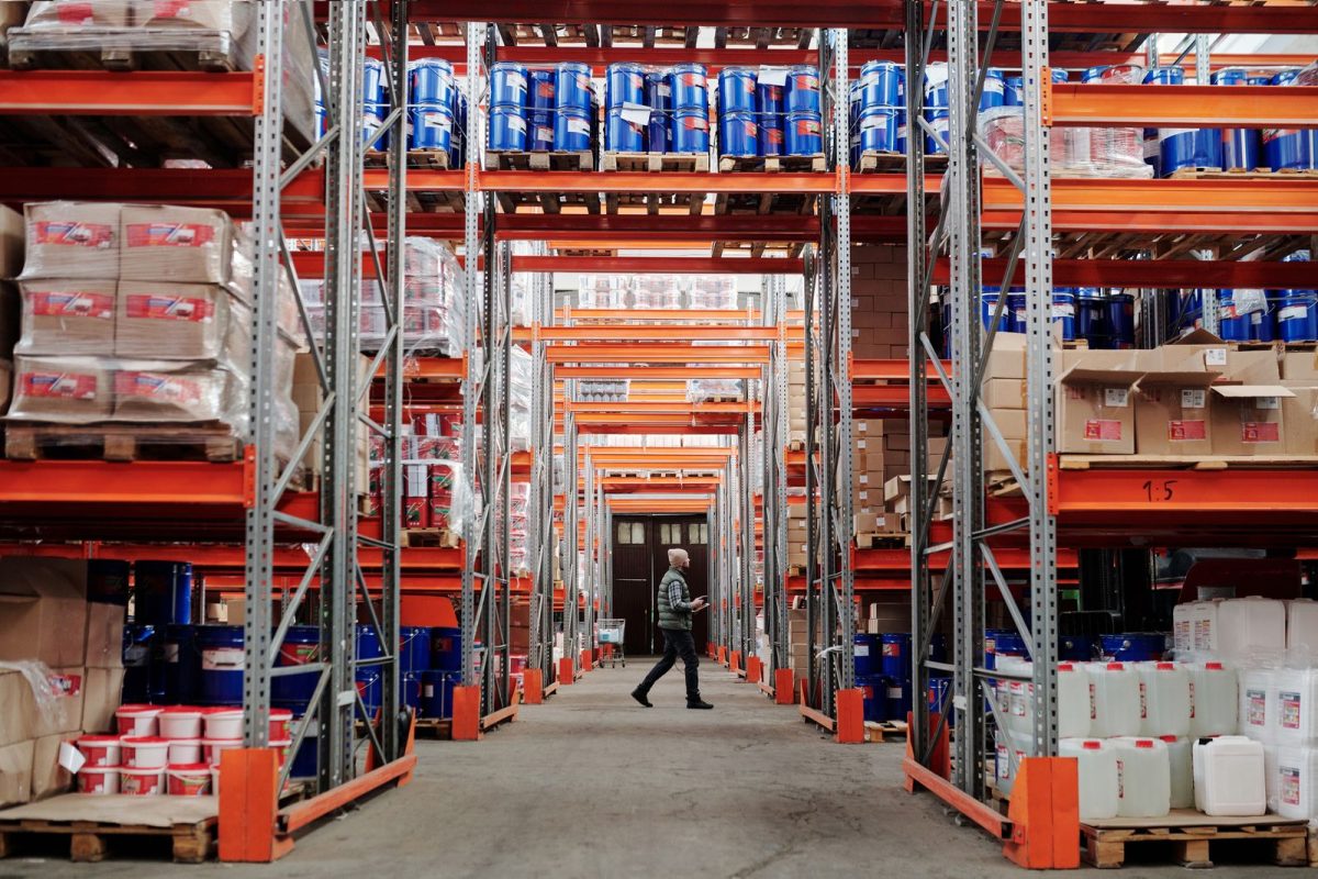 allee dans un entrepot de bricolage avec etageres orange et employe