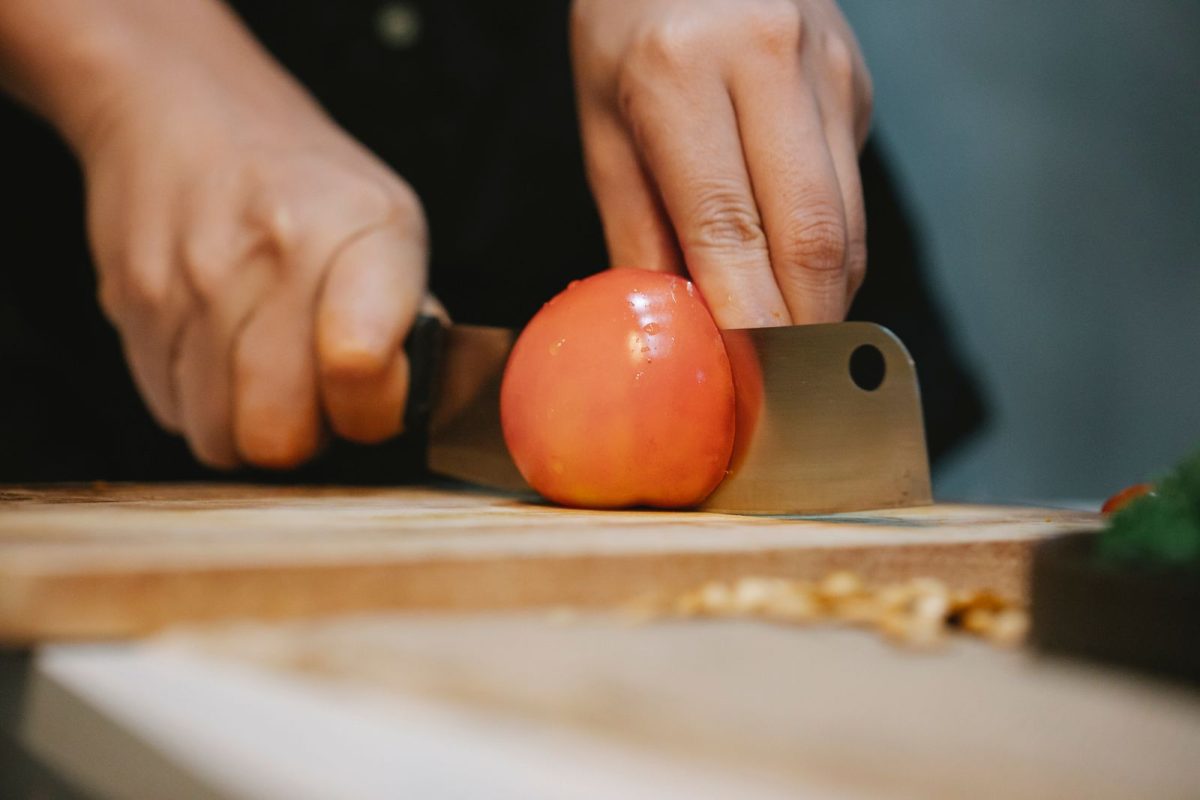 Mains coupant une tomate au couteau sur planche a decouper