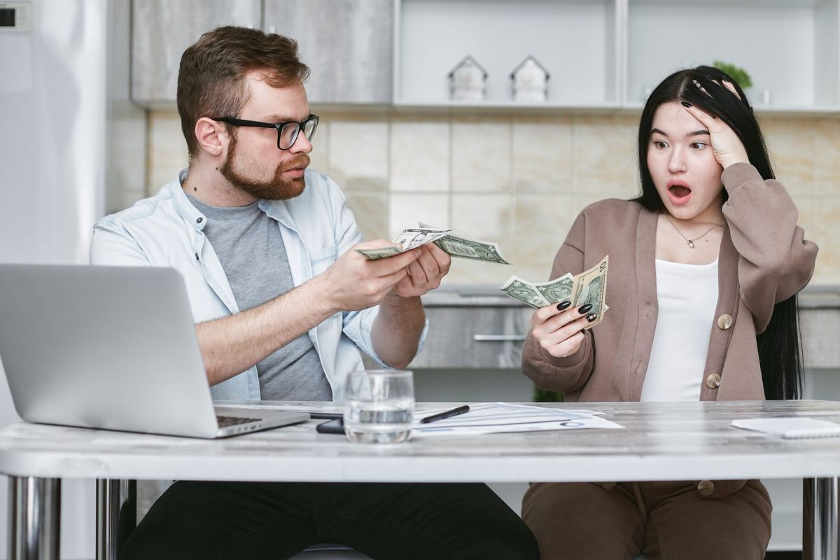 Un couple assis a une table examine ses finances avec un ordinateur portable.