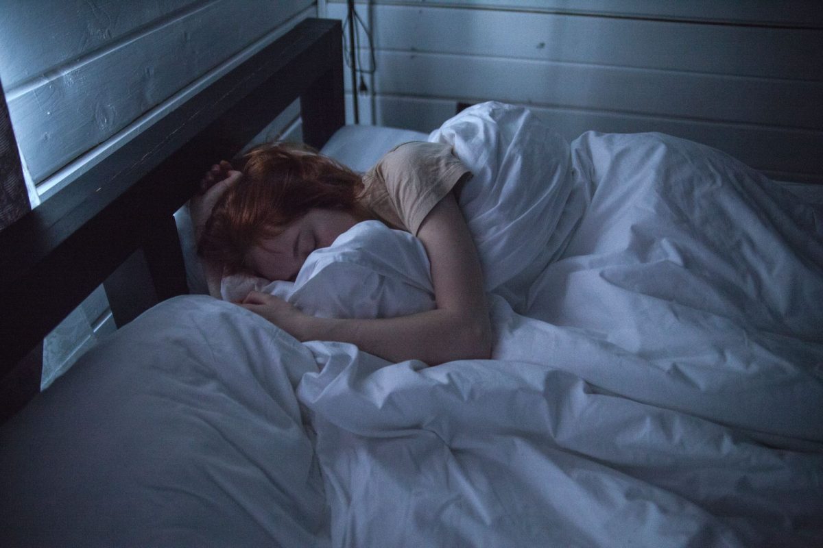 Femme allongee et endormie paisiblement dans un lit douillet, sous une lumiere tamisee de nuit