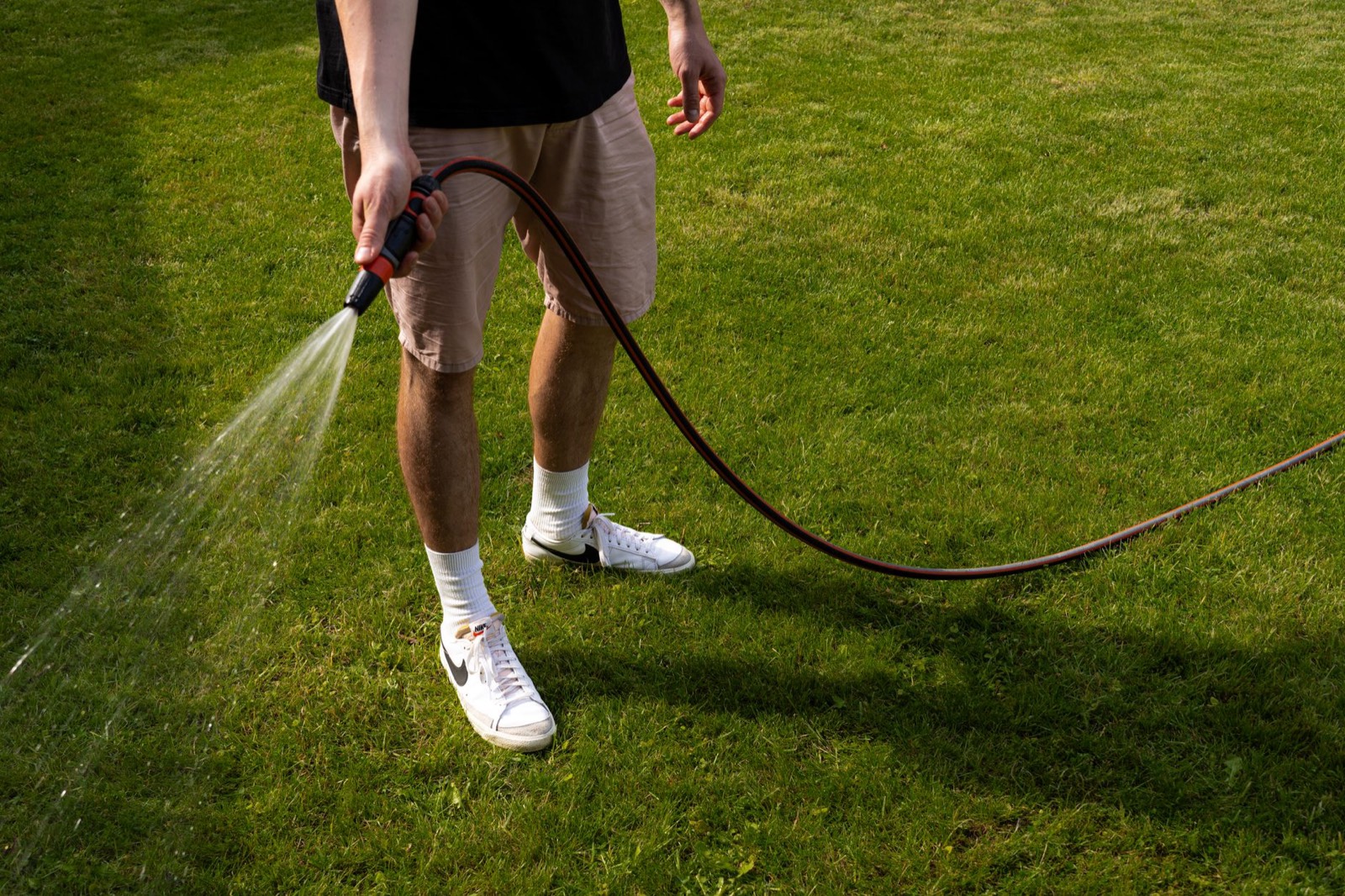 Tuyau d'arrosage et arrosoir posés dans un jardin avant une fête en extérieur